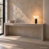 Vian Linden Marble Table Lamp in Black, glowing on a pale console.