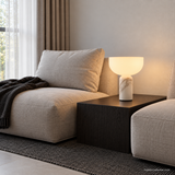 Vian Linden Marble Table Lamp in White, glowing beside low modular seating.