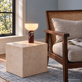 Vian Linden Marble Table Lamp in Dark red, glowing beside a cane-backed reading chair.