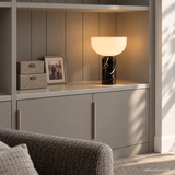 Vian Linden Marble Table Lamp in Black, glowing in gray shelving.