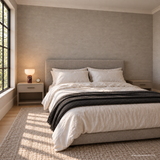 Vian Linden Marble Table Lamp in Dark red, glowing on a bedside table against a woven wall.